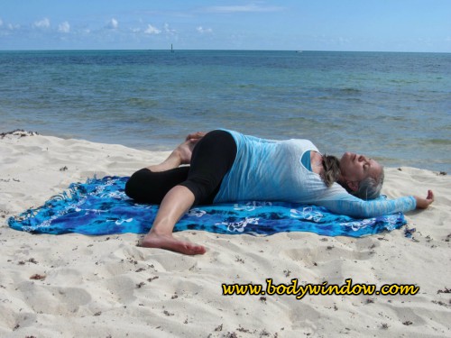 Reclining Cat Pulling Its Tail Pose, being done on a beach in Playa del Carmen, Mexico.