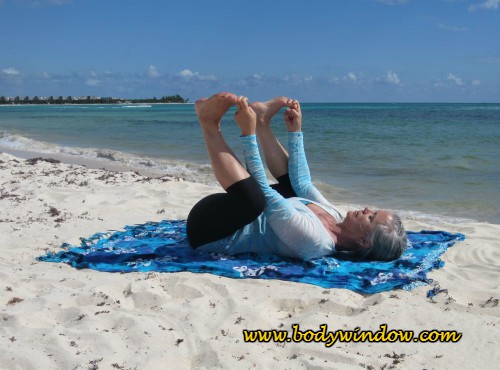 Happy Baby Pose with "Peace Fingers" Hand Position, being done on a beach in Playa del Carmen, Mexico.